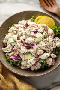Bowl of homemade chicken salad with fresh vegetables and herbs