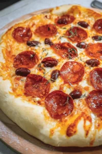 Homemade pizza with fresh ingredients and toppings on a wooden table.