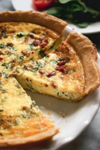Delicious slice of perfect quiche with a flaky crust and colorful vegetables
