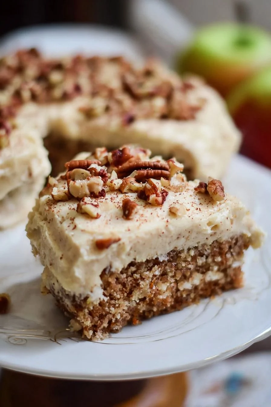 Slice of apple pecan spice cake with brown sugar cream cheese frosting on a plate.