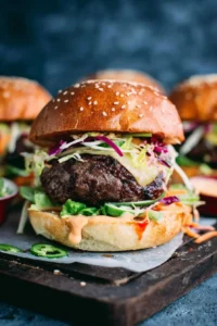 Asian barbecue burgers topped with sweet chili lime mayo on a grill