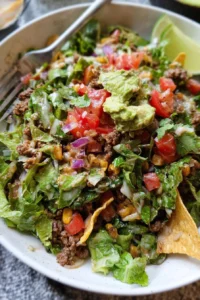 Delicious beef taco salad topped with fresh veggies and creamy dressing