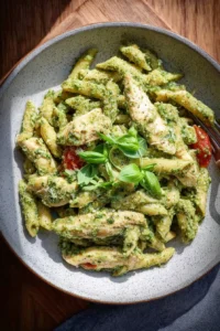 Delicious Chicken Pesto Pasta topped with fresh basil and grated cheese