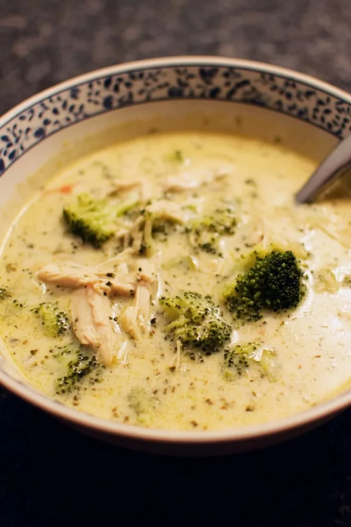 Bowl of creamy chicken broccoli soup garnished with herbs