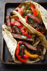 Plate of grilled steak fajitas with peppers and onions