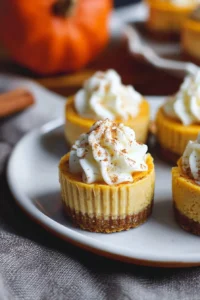 Delicious mini pumpkin cheesecakes topped with whipped cream and spices
