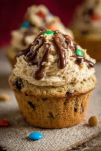 Monster cookie dough cupcakes topped with creamy frosting and cookie dough bits.