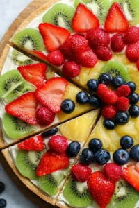 Delicious fruit pizza topped with colorful fresh fruits and cream