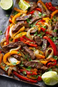 Sheet pan steak fajitas with colorful peppers and onions on a table