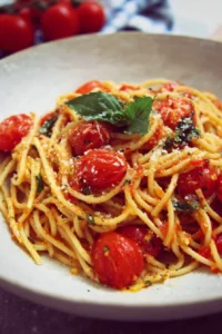 Bowl of Simple Spaghetti Margherita topped with fresh basil and tomatoes.