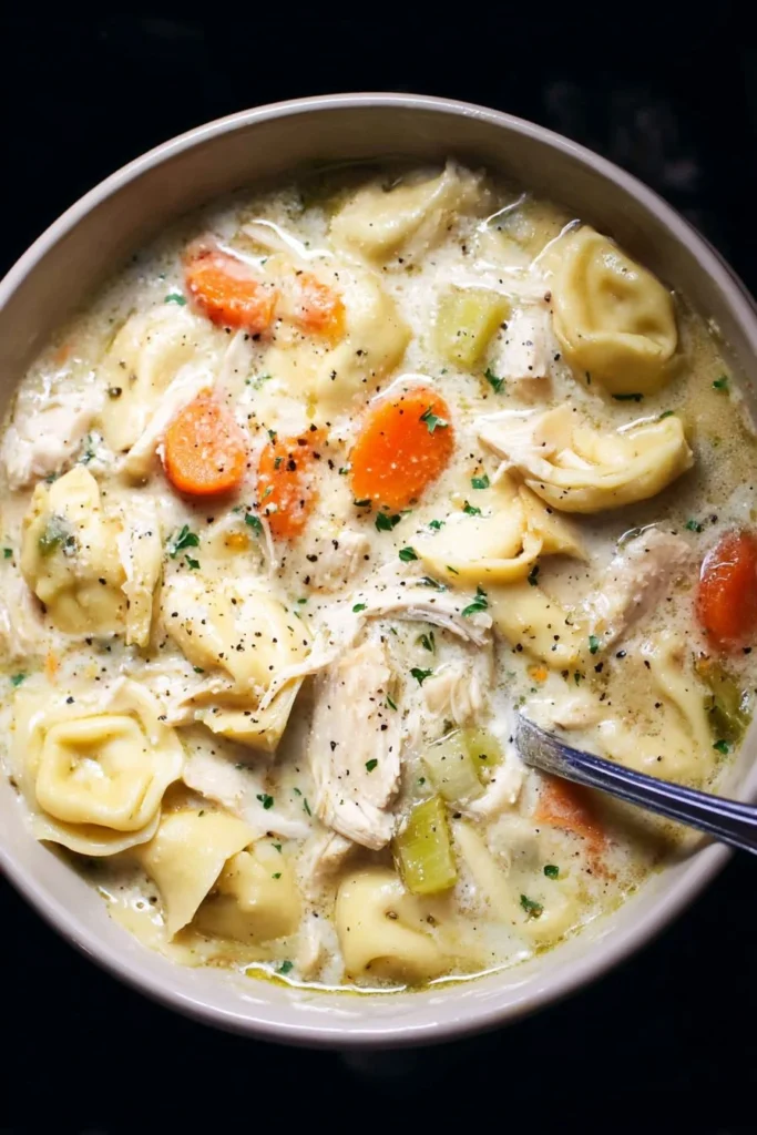 Creamy chicken tortellini soup in a slow cooker with fresh ingredients.