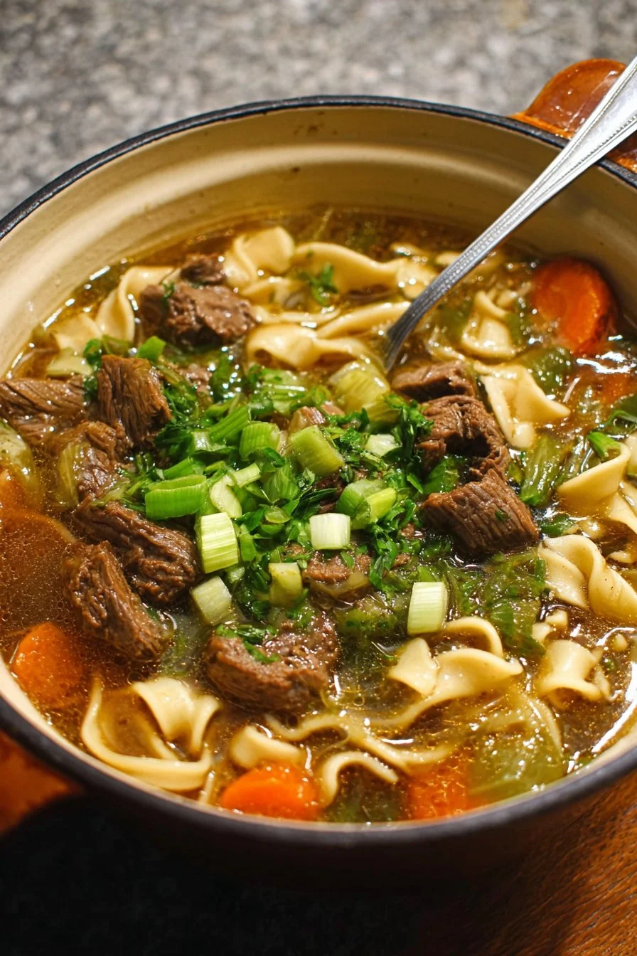Bowl of delicious Beef Noodle Soup garnished with herbs and spices