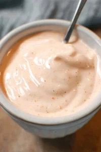 Creamy Thousand Island dressing in a bowl with fresh ingredients around it
