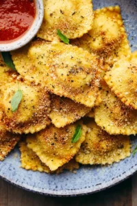 Crispy baked parmesan ravioli served on a plate with marinara sauce.