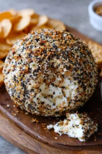Everything bagel cheese ball served on a platter with crackers and veggies
