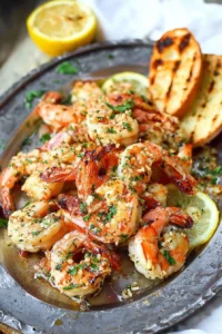 Grilled garlic butter shrimp served on a plate with lemon and herbs