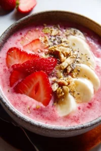 Delicious strawberry smoothie bowl topped with fruits and granola