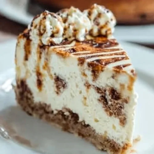 Delicious cinnamon roll cheesecake topped with cinnamon and cream cheese icing.
