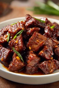Delicious glazed sticky beef bites garnished with sesame seeds and herbs