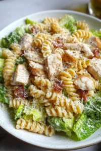 Delicious Chicken Caesar Pasta Salad served in a bowl with dressing and greens