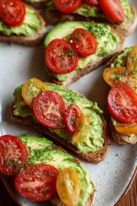 Creamy garlic tomato avocado toast served on a white plate with fresh herbs