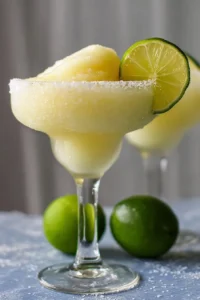 Delicious frozen margarita served in a glass with lime and salt rim.