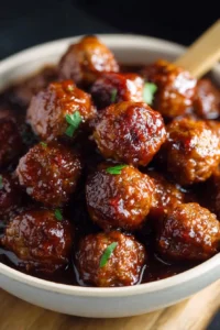 Bowl of slow cooker honey garlic meatballs with garnish.