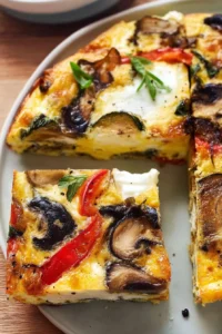 Baked vegetable frittata topped with colorful vegetables and herbs