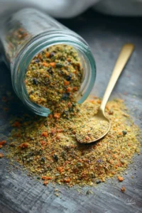 Bowl of homemade Vegeta seasoning with fresh herbs and spices.