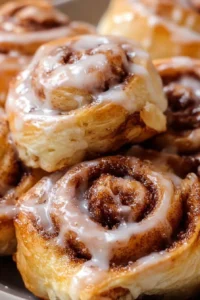 Delicious puff pastry cinnamon rolls with icing on a wooden table