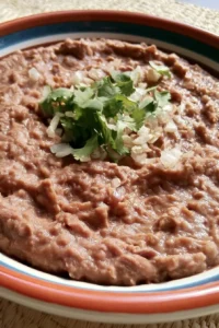 Bowl of authentic Mexican refried beans garnished with cilantro