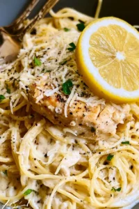 Creamy lemon chicken pasta dish garnished with herbs on a plate.