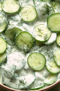 Fresh cucumber yogurt salad garnished with herbs in a bowl.
