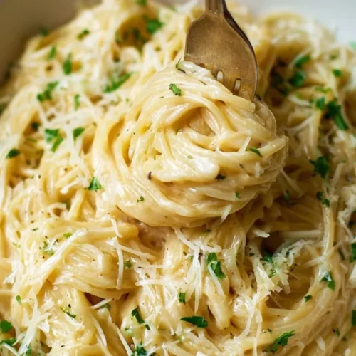 Long pasta coated in creamy sauce with cheese and herbs