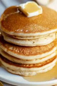 A bowl of homemade pancake mix with ingredients for fluffy pancakes