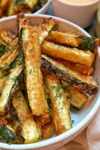 Plate of crispy keto gluten-free zucchini fries garnished with herbs
