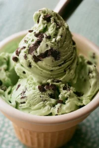 Delicious mint chocolate chip ice cream in a bowl with chocolate chips and mint leaves