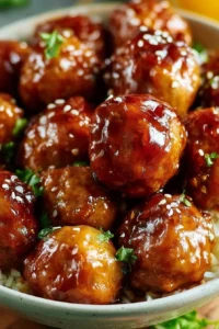 Plate of slow cooker teriyaki meatballs garnished with sesame seeds and green onions.