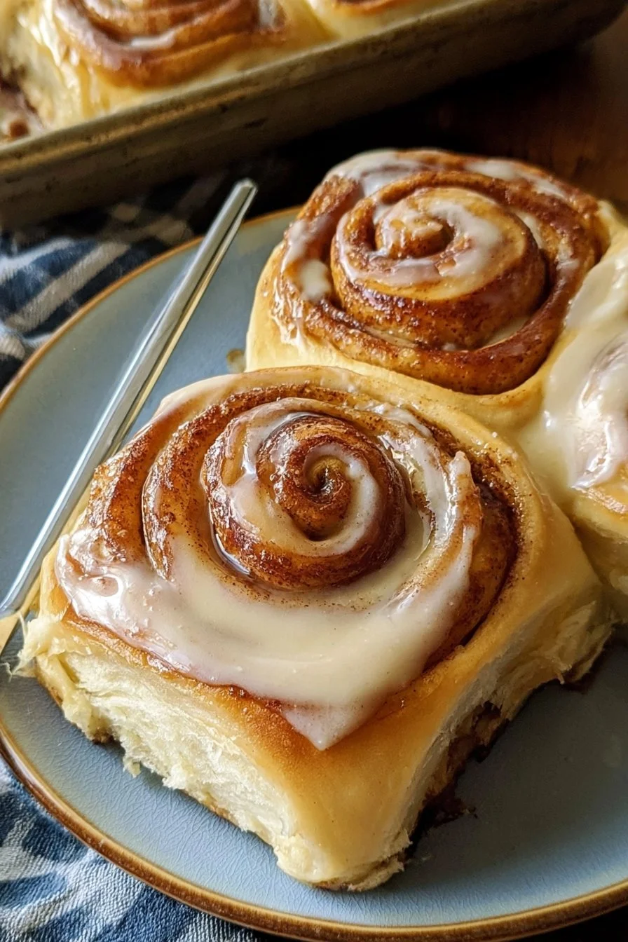 Freshly baked sourdough cinnamon rolls topped with icing on a wooden table.